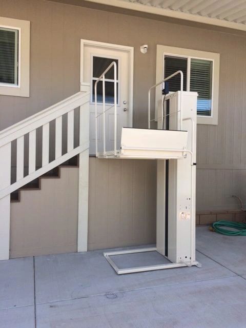 A porch lift installed beside a flight of exterior stairs